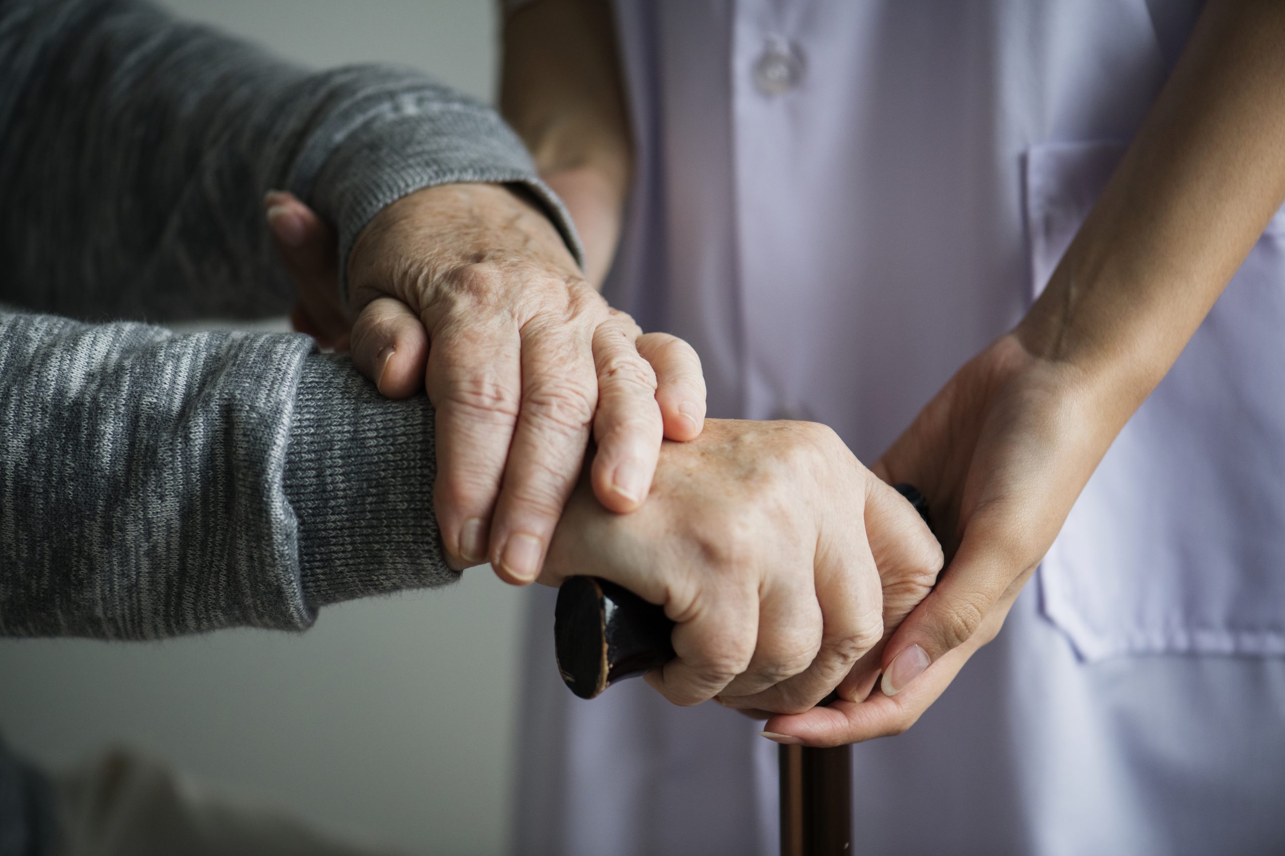 Compassionate nurse holding patient’s hand at home during end-of-life care in Phoenix.