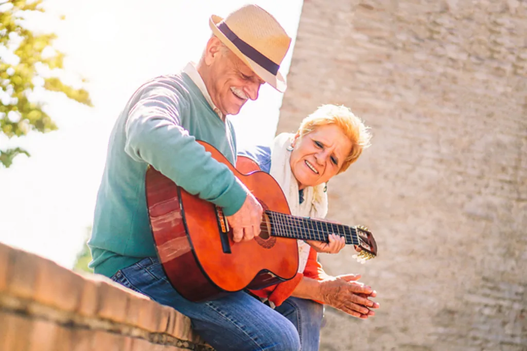 Older couple playing guitar together outdoors