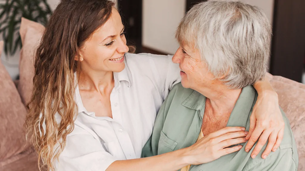 Adult daughter embracing her mother on a couch at home
