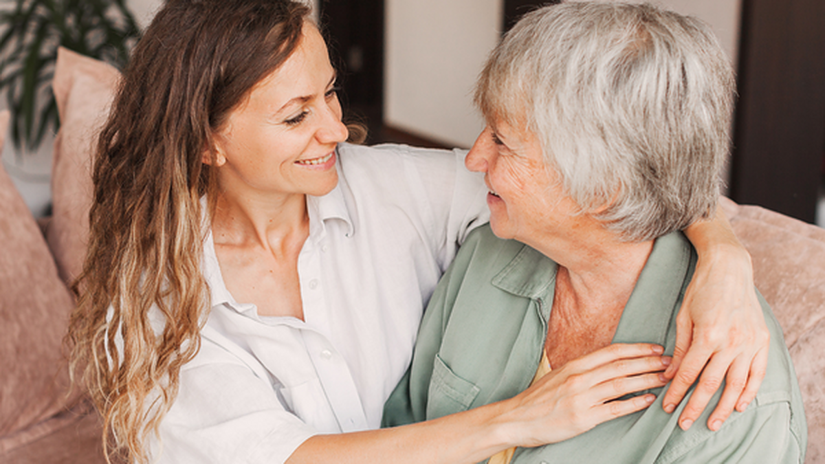 Adult daughter embracing her mother on a couch at home