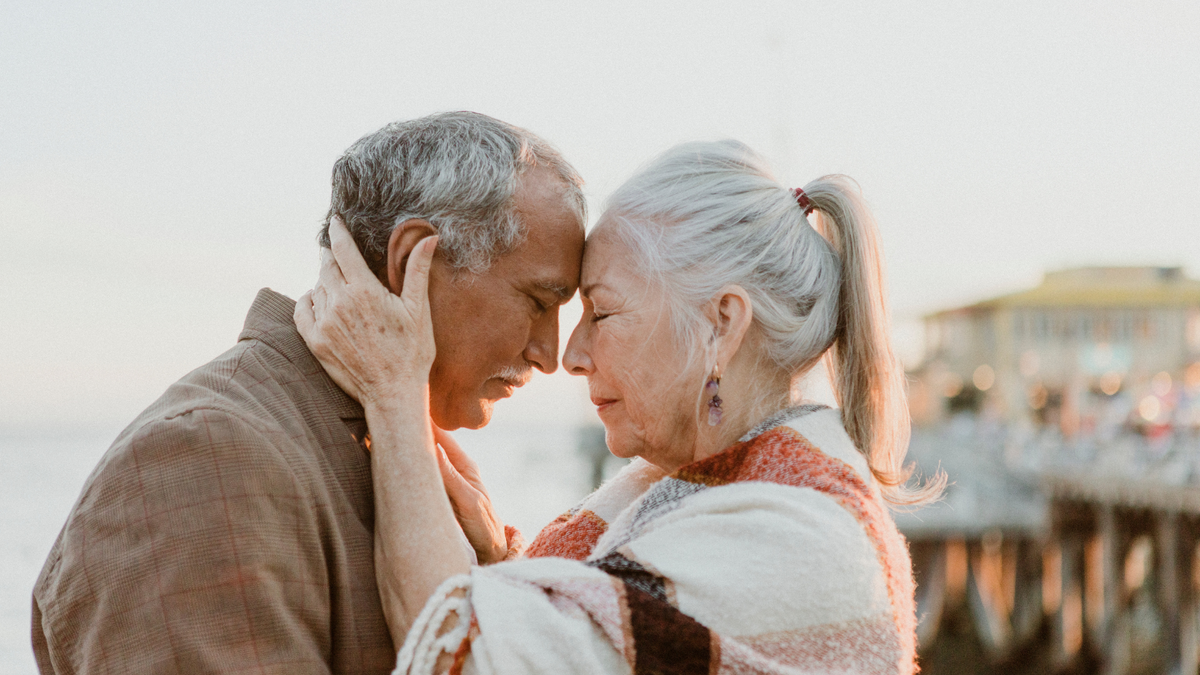 Older couple resting their foreheads together outdoors at sunset